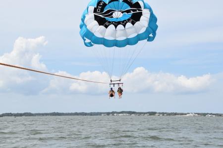 Two people parasailing in Dewey Beach on a nice day.