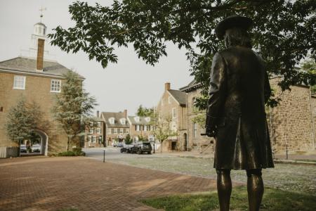 The back of a historic statue facing streets and buildings of Historic New Castle.