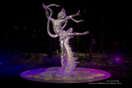 a large lighted ice sculpture of a dancer outdoors