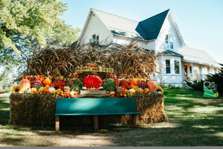 Berryland sign and pumpkin display with large historic white house in the background.
