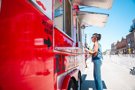Woman ordering food at the service window of the El Bistro Taco food truck.