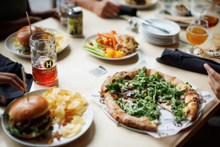 Pizzas, Burgers, and drinks from Hinterland Brewery all sitting on a table waiting to be eaten.