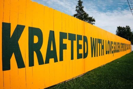 Yellow Fence with Green Lettering that reads "Krafted with love, golden opportunity, and smack on target."