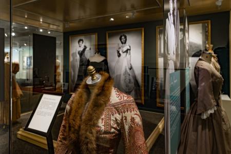 Costumes on exhibit in front of large pictures of Ava Gardner