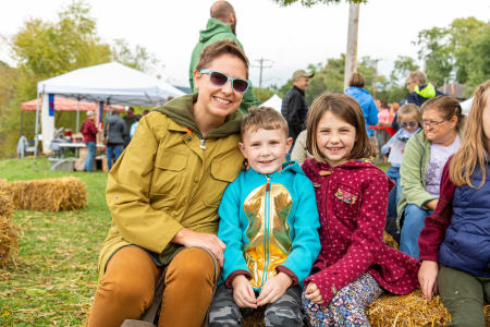 Family poses for a picture on a hay bale.