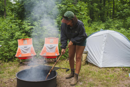 A woman practicing proper fire etiquette by dispersing ashes in a fire pit
