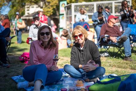 Two women sitting on blankets at the McKinney Wine & Music Festival