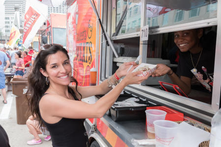 woman receiving a boat of food from a food truck during taste of cincinnati at fountain square