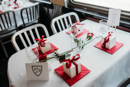 Valentine's day themed table setting on a train, white boxes with red ribbons are placed at each seat