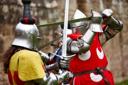 Two medieval knights in costumer fighting with swords