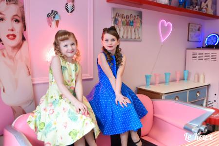 Two little girls dressed in vintage outfits in a pink studio