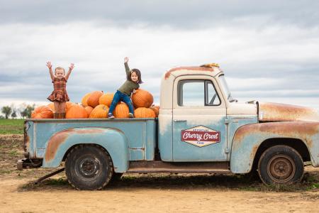 children in back of vintage truck with pumpkins at Cherry Crest Adventure Farm