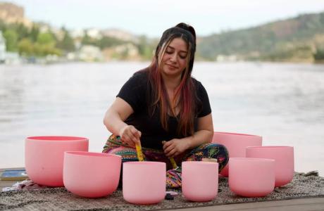 Woman facilitates a "Sound Bath" with singing bowls