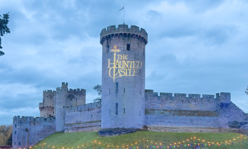 Warwick Castle with the words 'The Haunted Castle' displayed onto the castle walls