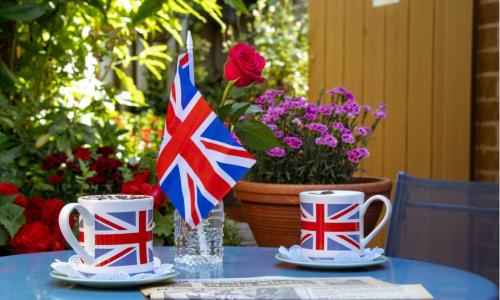 Two cups of tea decorated with the Union Jack and a Union Jack flag on a table