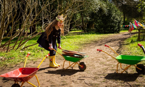 A girl collecting things in a green wheelbarrow