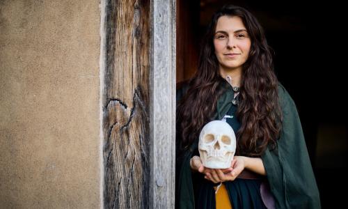 A female costumed actor holding the skull of Hamlet in the doorway of Shakespeare's Birthplace