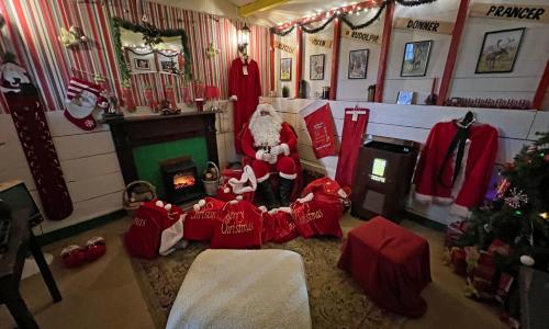 Santa Claus sitting in the corner of a traditionally decorated room next to a log burner