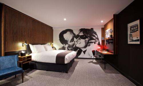 A contemporary hotel bedroom with a full wall covered by a black and white mural