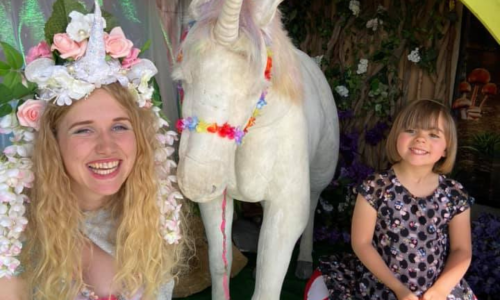 A woman and a young girl sitting next to a unicorn