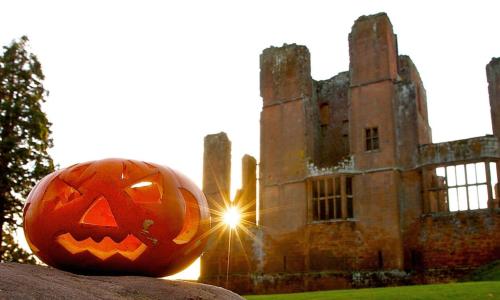A carved pumpkin sitting on a rock in front of Kenilworth Castle