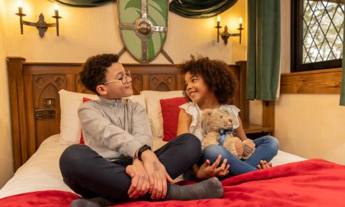 Two children sitting on a mediaeval themed bed at Warwick castle