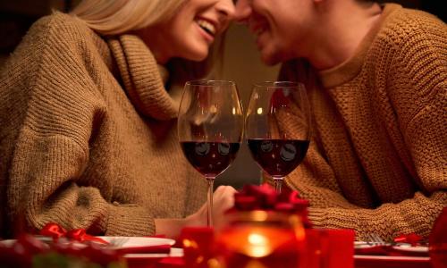 A couple chatting and smiling over two glasses of red wine