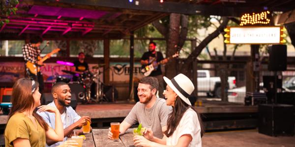 A group of people with drinks in front of a stage.