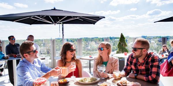 A group of friends enjoying cocktails and appetizers on the rooftop patio at VASO on a sunny day.