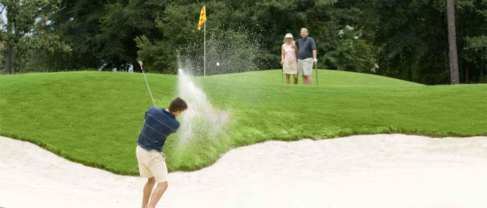 a man swinging a golf club in a sand trap