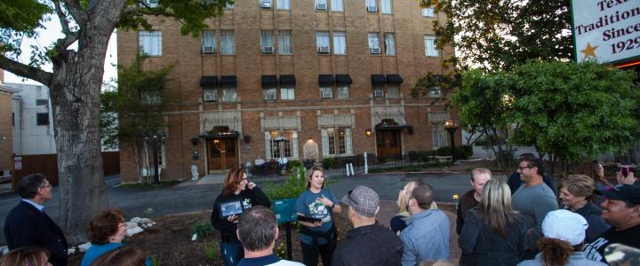 A small group stands in front of the haunted Faust Hotel on a ghost tour in New Braunfels, Texas.
