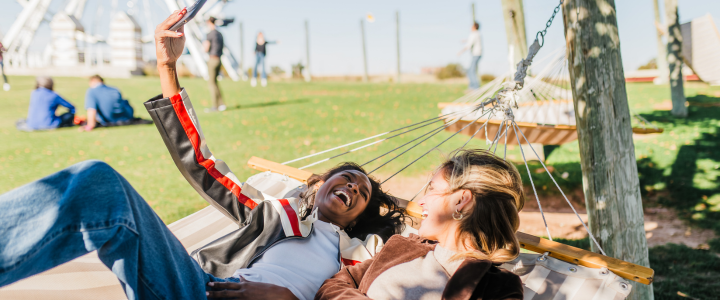Two girls laying in a hammock in front of the Wheeler Ferris Wheel