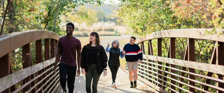 Two couples walking across a bridge at Stinchcomb Refuge