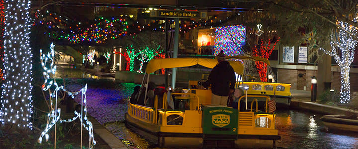 Bricktown Water Taxi cruising through the water surrounded by winter lights