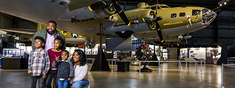 A family standing beneath the wing of the B-17 bomber "Memphis Belle" at the National Museum of the U.S. Air Force