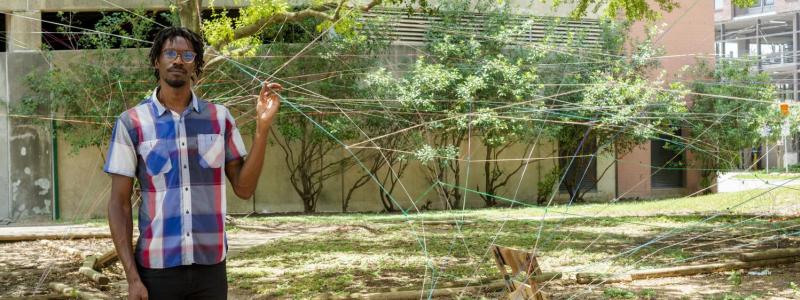 Image of Ronald Llewellyn Jones in one of his string sculptures constructed outdoors.