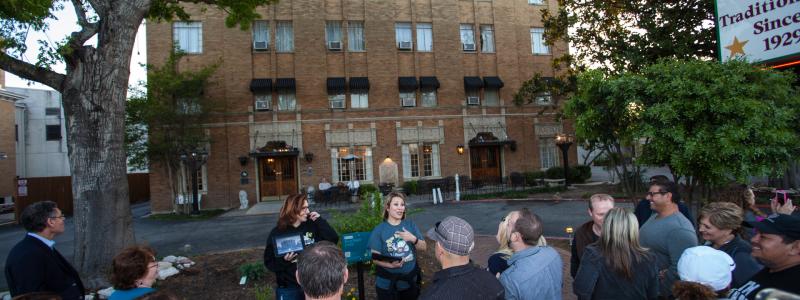 A small group stands in front of the haunted Faust Hotel on a ghost tour in New Braunfels, Texas.