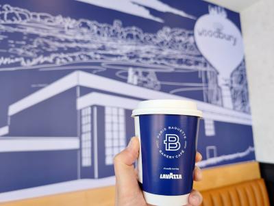 Mural of Woodbury inside Paris Baguette while holding a coffee in front