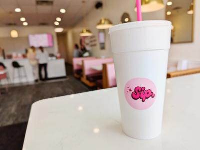 Close up of Sig. Dirty Soda drink in the store with customers ordering in the background