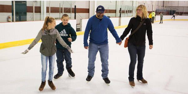 family holding hands while ice skating