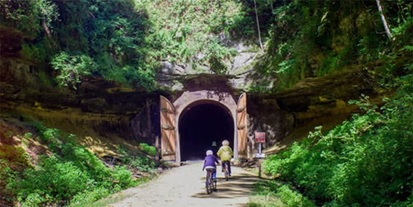 An old railroad tunnel opens up to a gravel bike path