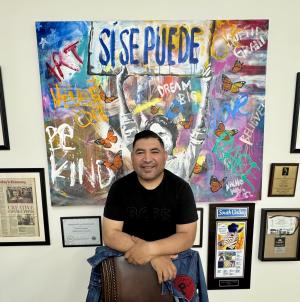 Ignacio "Nacho" Moya with a large painting of Delores Huerta holding "SI SE PUEDE"