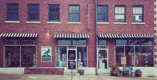 Exterior of the Raven Bookstore, with red brick walls and black and white striped awnings.