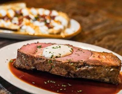 A medium-well steak sits on top of a plate garnished with butter and fresh herbs at StoneHouse, Fort Smith, Arkansas.