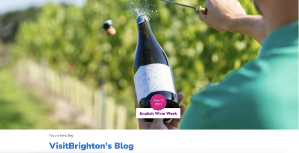 A wine bottle is being opened by a man in a teal shirt at the top of Visit Brighton's Blog