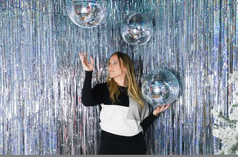 Woman with silver streamers and three disco balls.