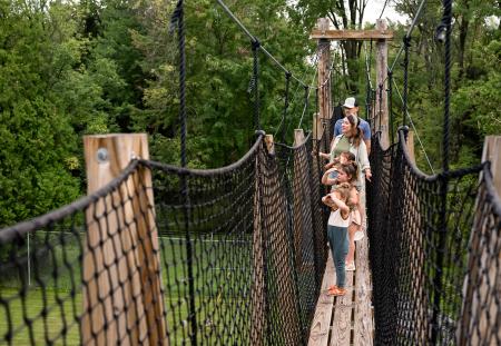 Family of five at NEW Zoo Adventure Park walking across the ropes course and looking into the distance