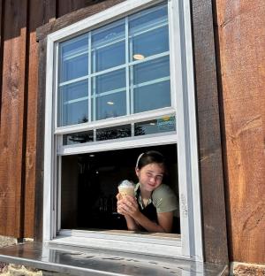 Girl holding coffee at the window of Old Mill Creamery