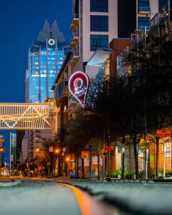 Exterior sign of Austin Visitor Center in downtown Austin from the street with Frost Bank tower behind