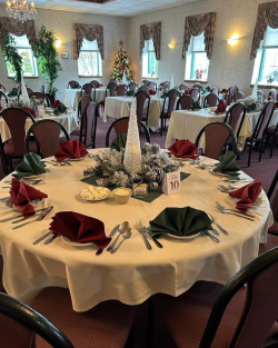 Picture of dining room at La Primavera Italian Restaurant all decorated for the Holidays with Christmas tree in the corner and beautiful holiday centerpieces on the tables.
